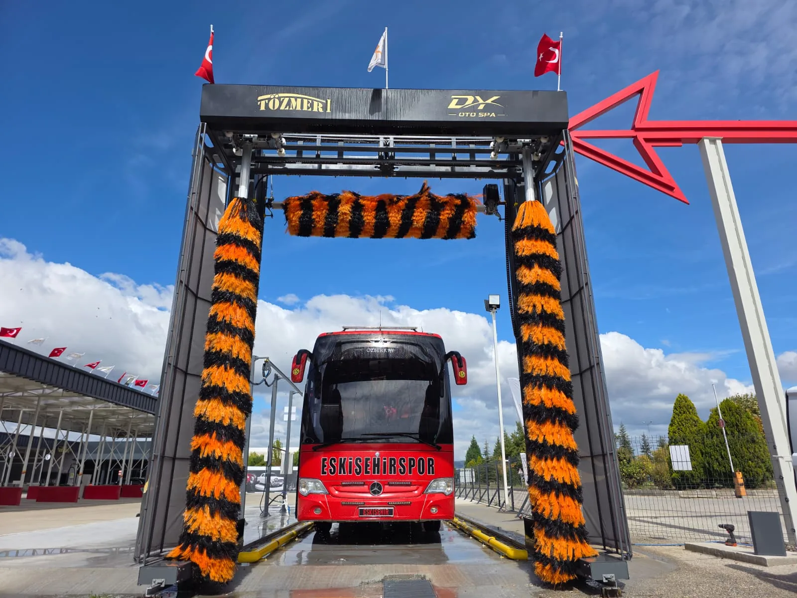 A red coach under the brushes of a SUNRISE gantry outdoors