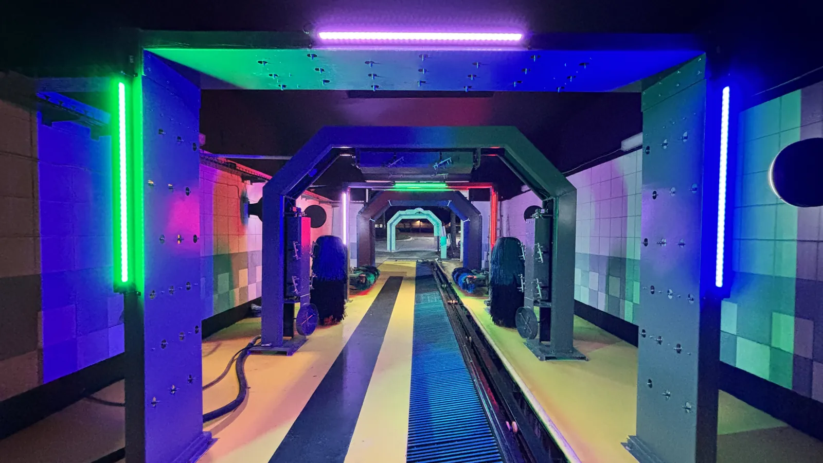 Interior of a Europe Makine conveyor tunnel, brushes and drying arches lit along the wash lane